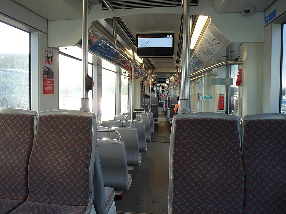 Tram interior with seats, aisle and grab rails near Tallinn Airport.