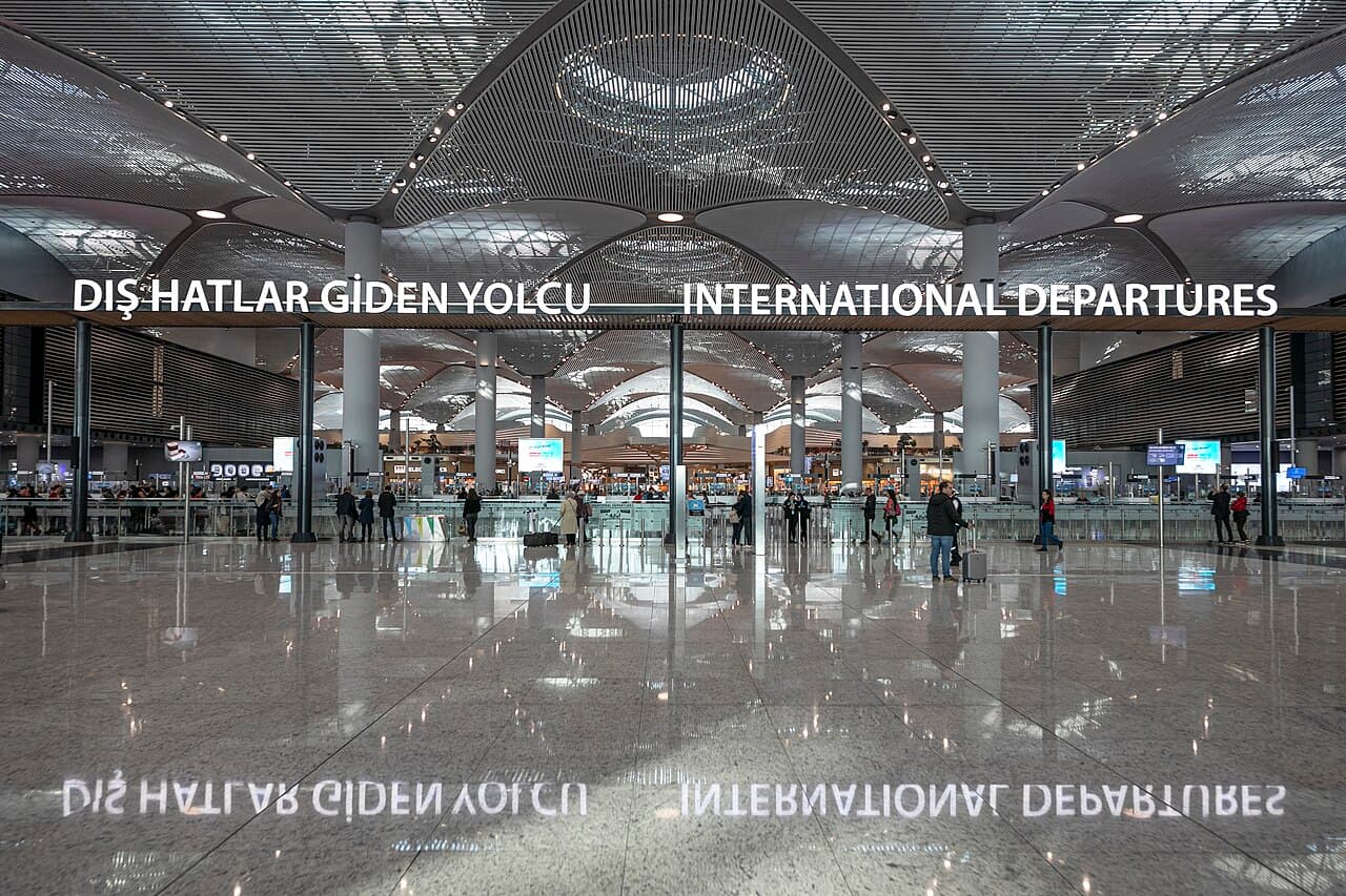 International departures hall at Istanbul Airport, with check-in signs and a high patterned ceiling.
