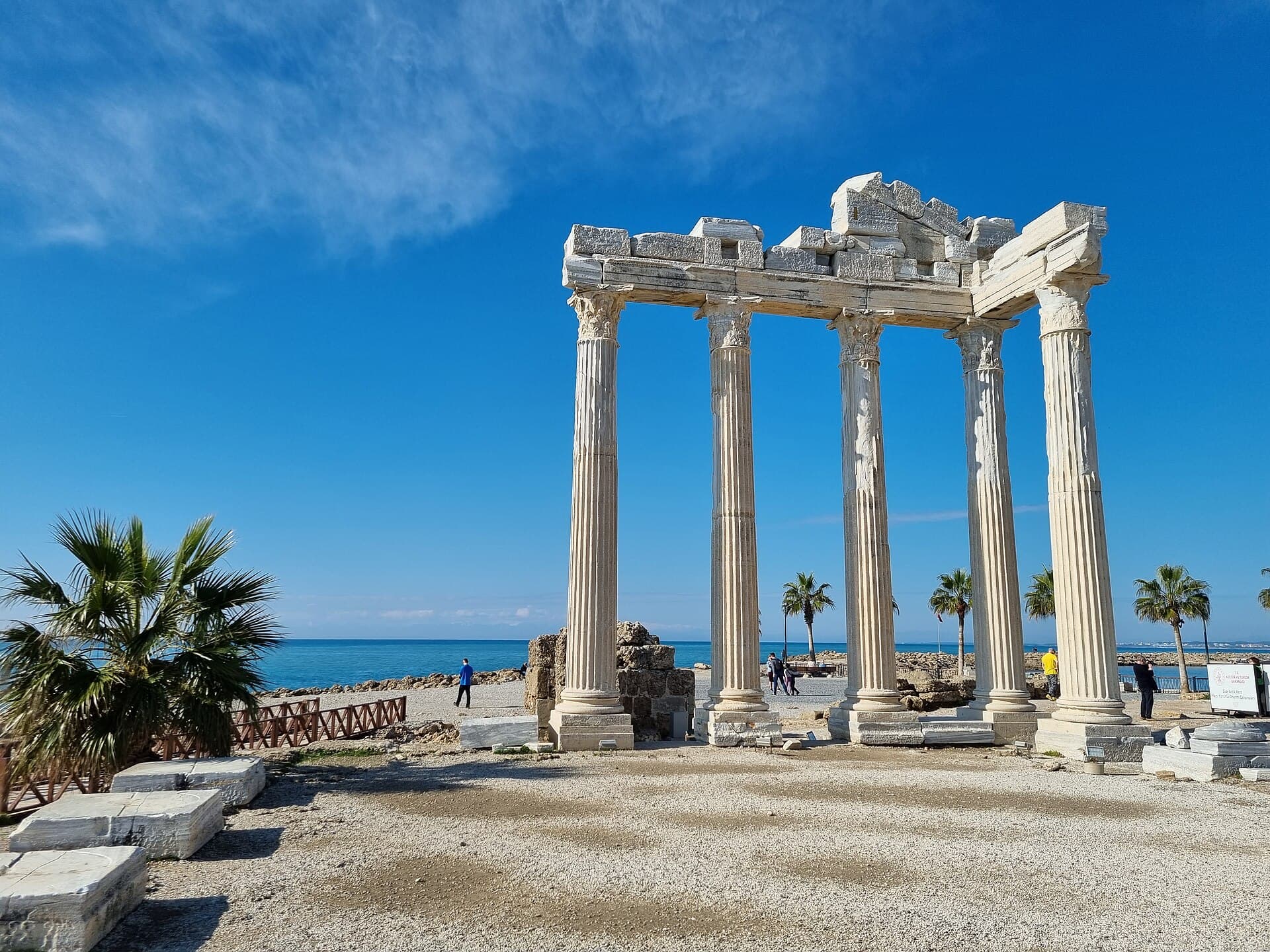 Sunlit columns of the Temple of Apollo at Side, with the sea and palms beyond.