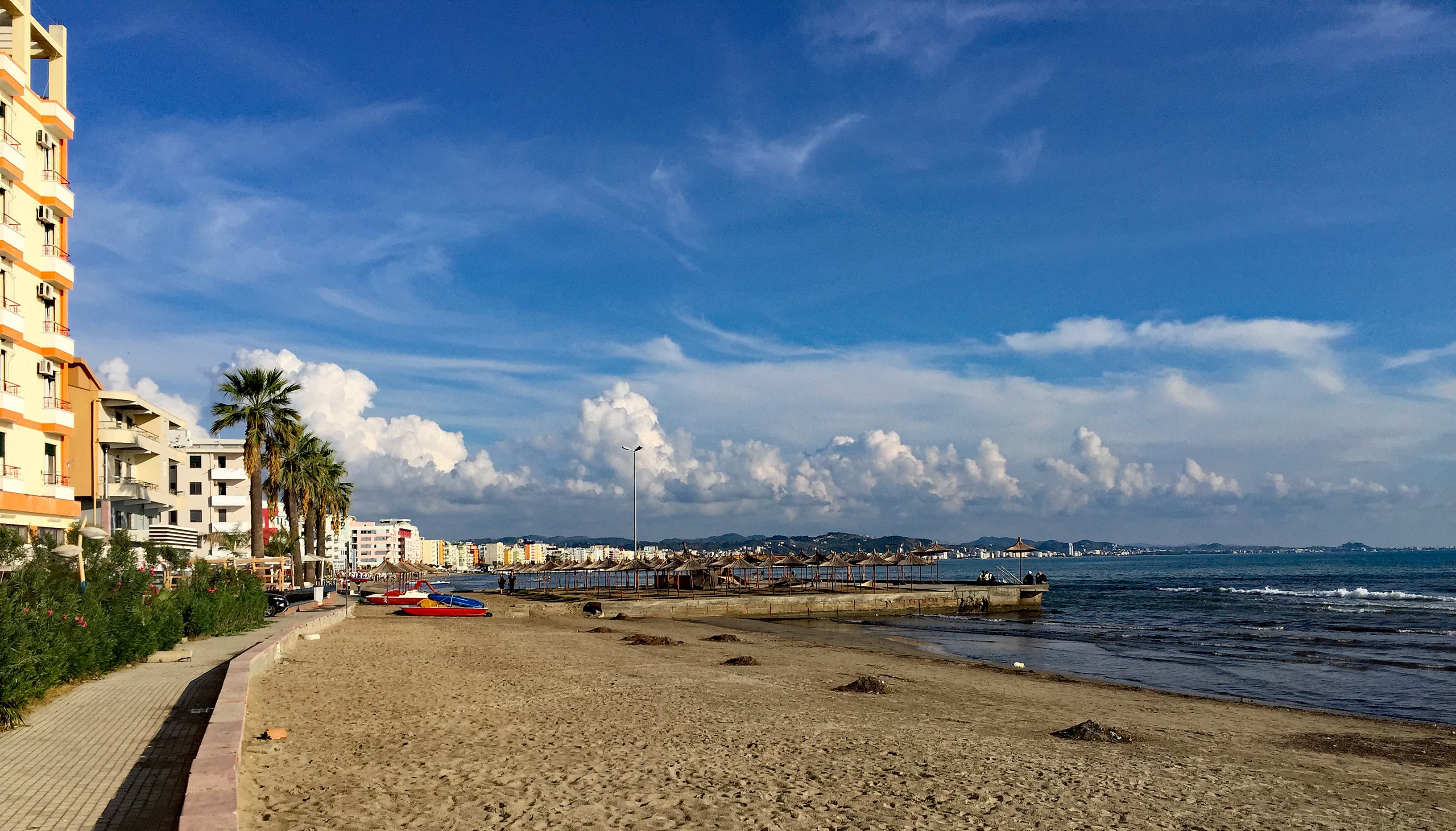 Beachfront buildings, a palm-lined walkway and the sea at Durrës Plazh.