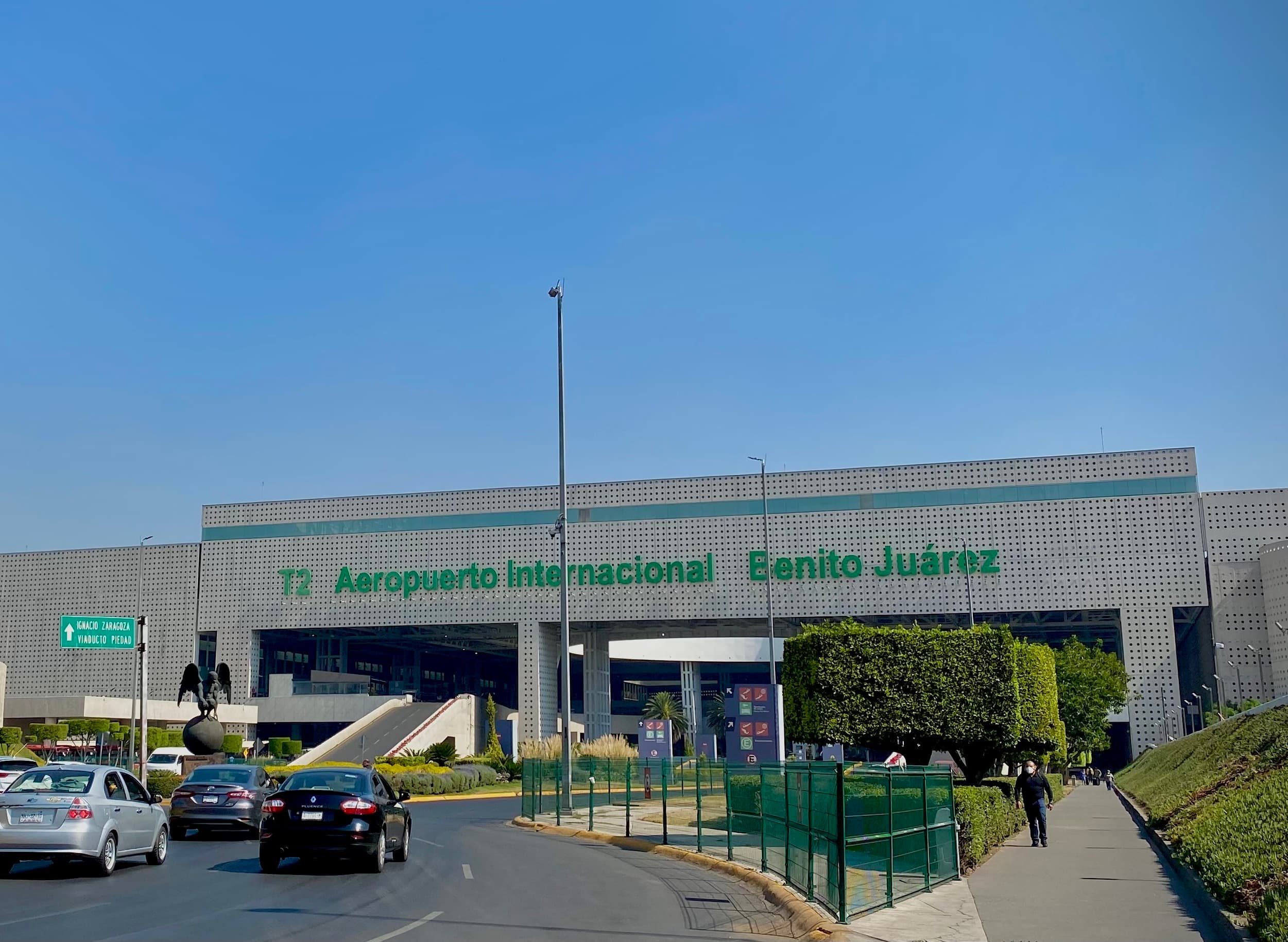 Terminal 2 facade at Mexico City International Airport with the Benito Juárez airport name and access road.