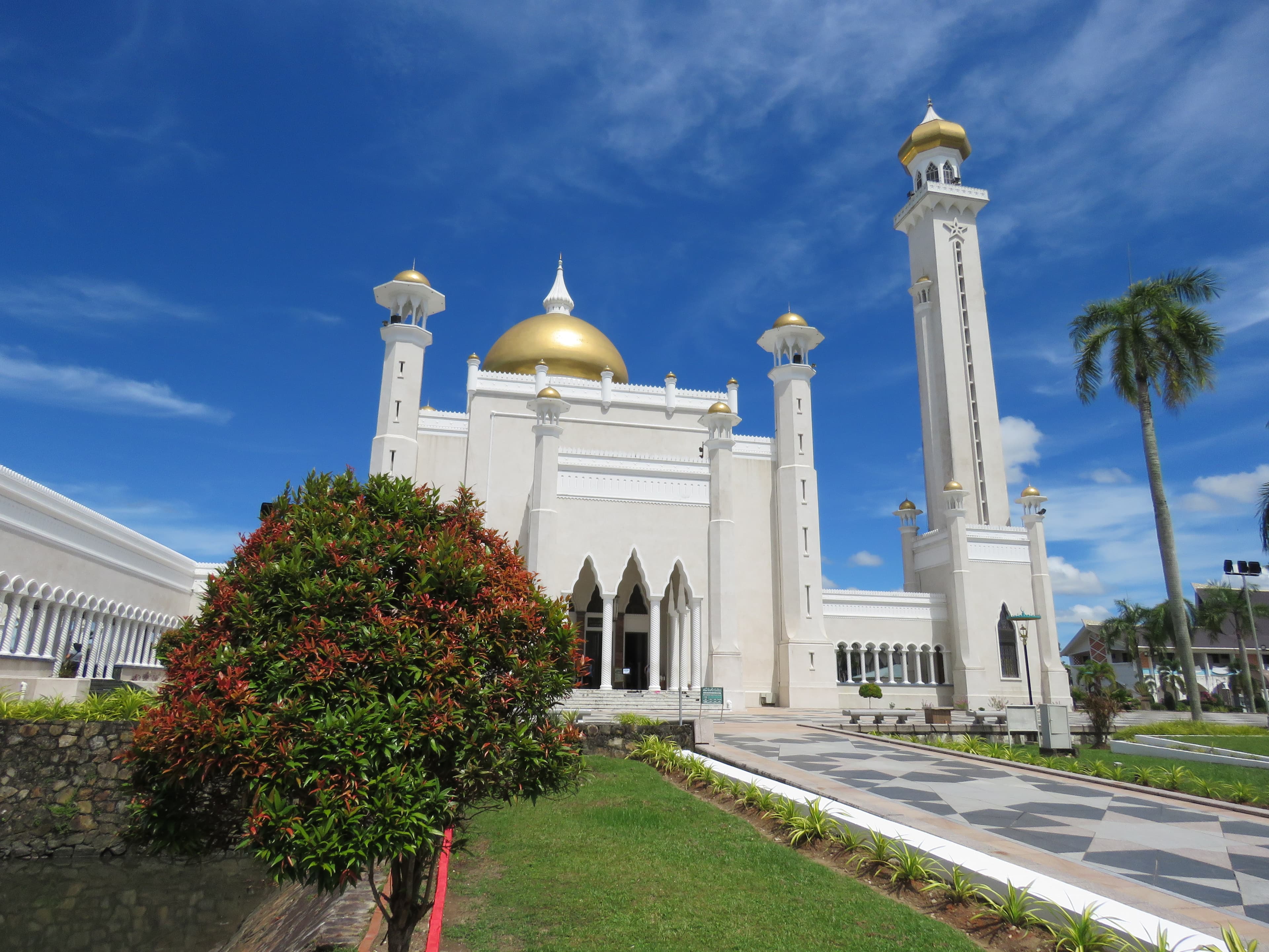 White walls and golden domes of Omar Ali Saifuddien Mosque against a blue sky in Bandar Seri Begawan.