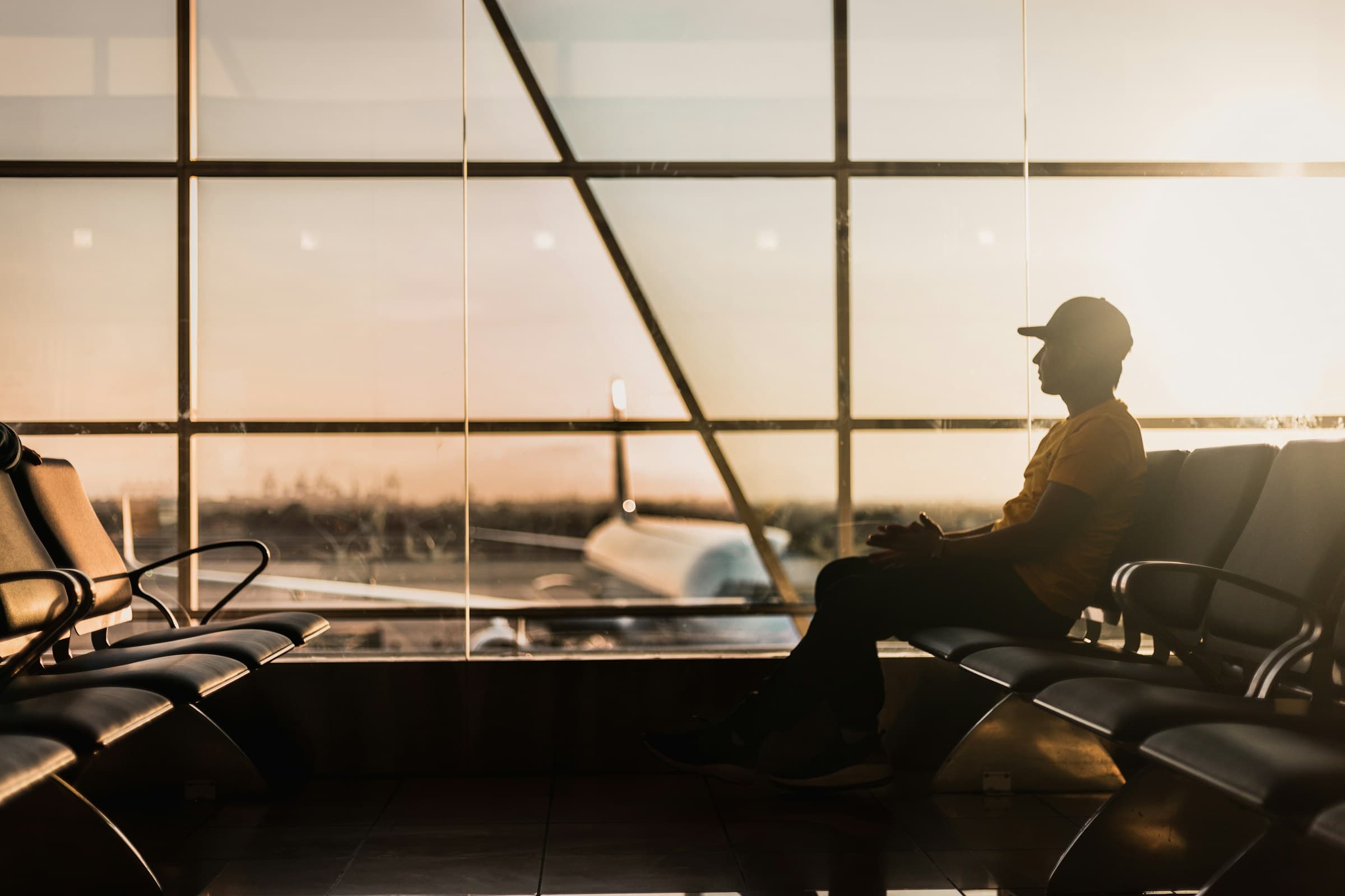 A traveller sitting beside the windows of an airport waiting area