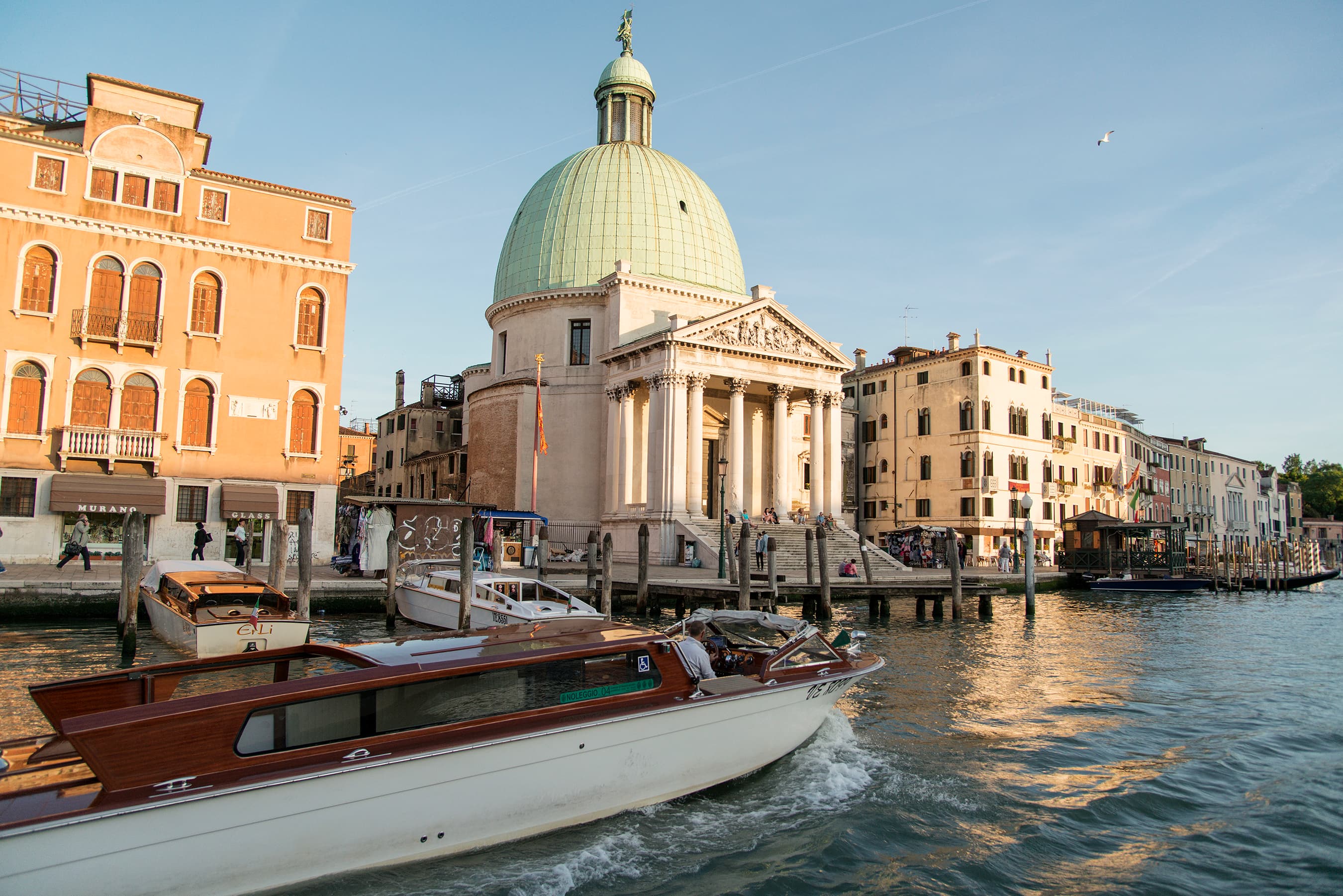 Wooden water taxi on Venice’s Grand Canal, with the dome of San Simeone Piccolo behind it
