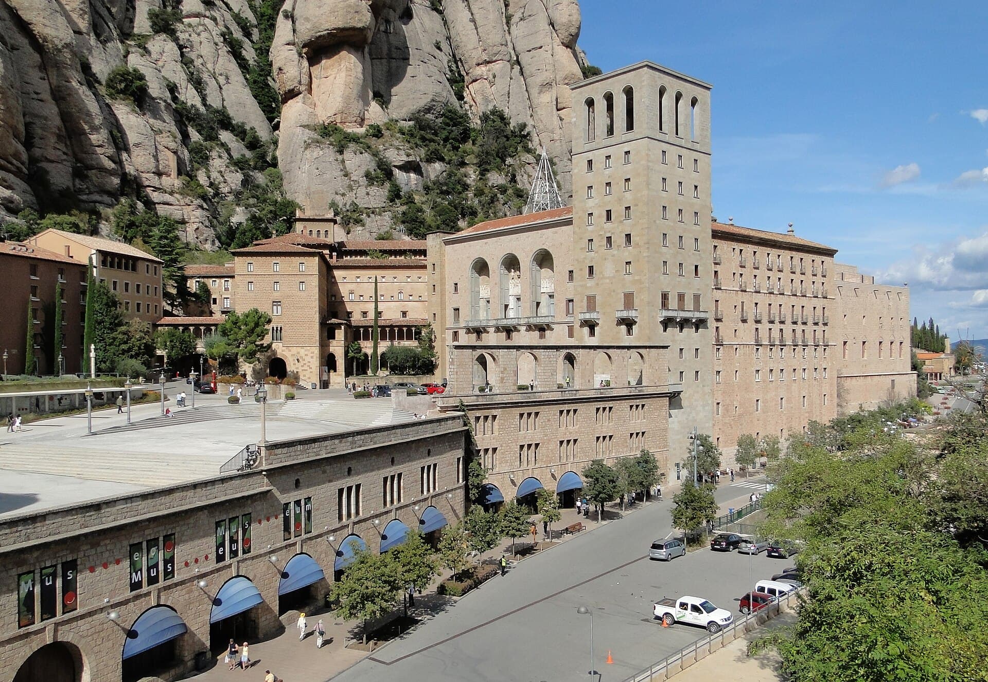 The Montserrat abbey complex beneath tall rounded rock formations under blue sky.