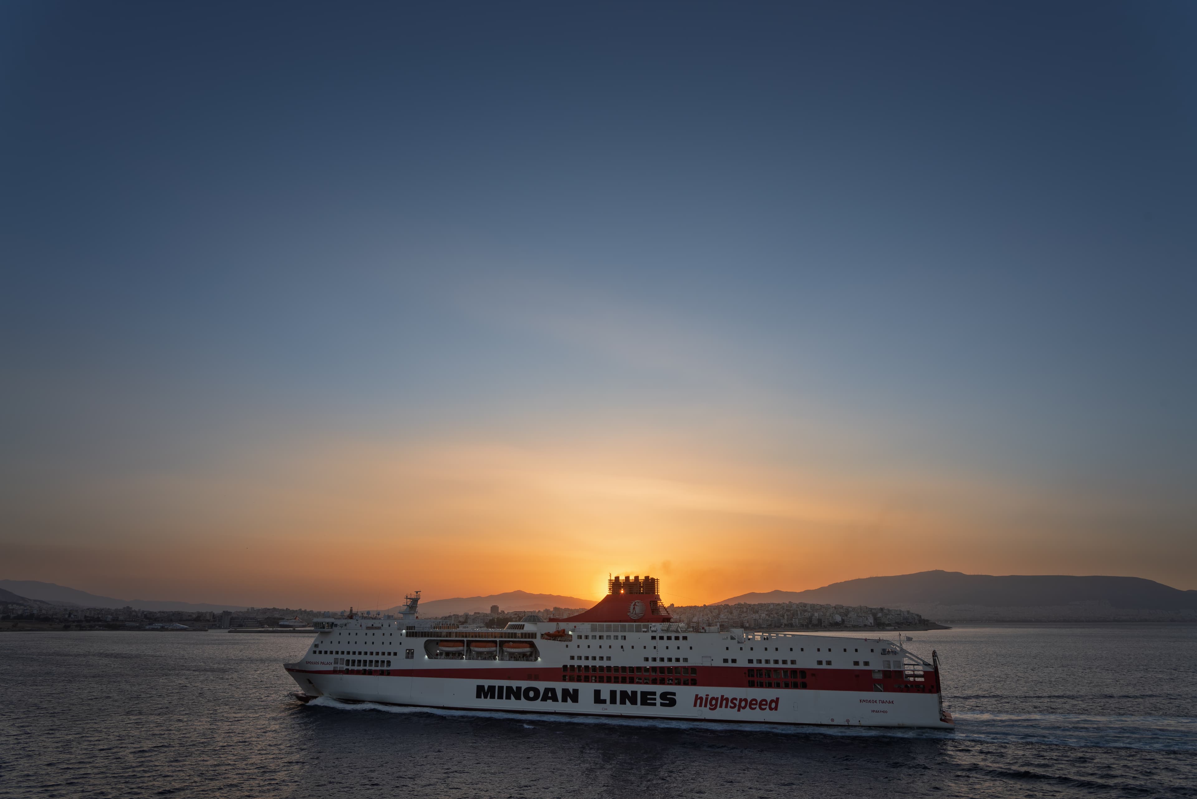 A passenger ferry in Piraeus Harbour against the rising sun.