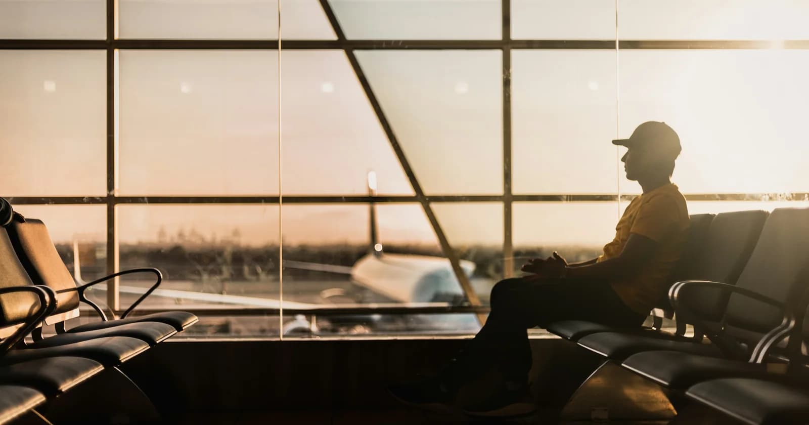 A traveller sitting beside the windows of an airport waiting area
