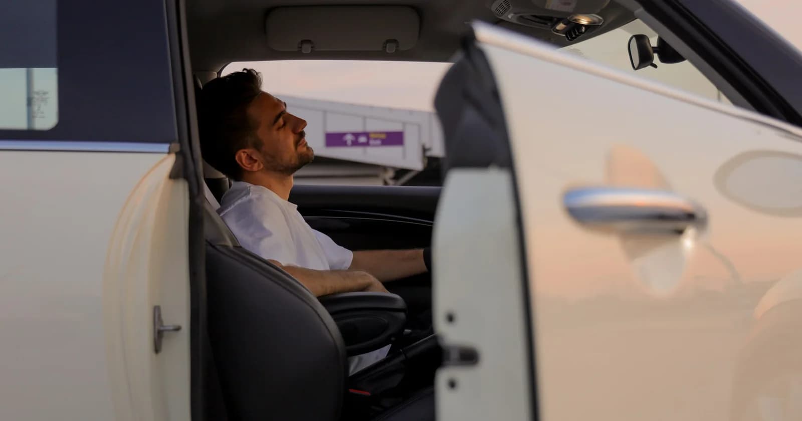 A man in the front seat of a parked car with the door open