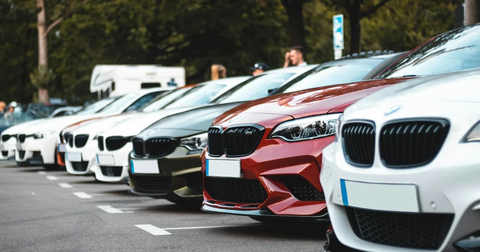 A row of parked sedans in white, green and red