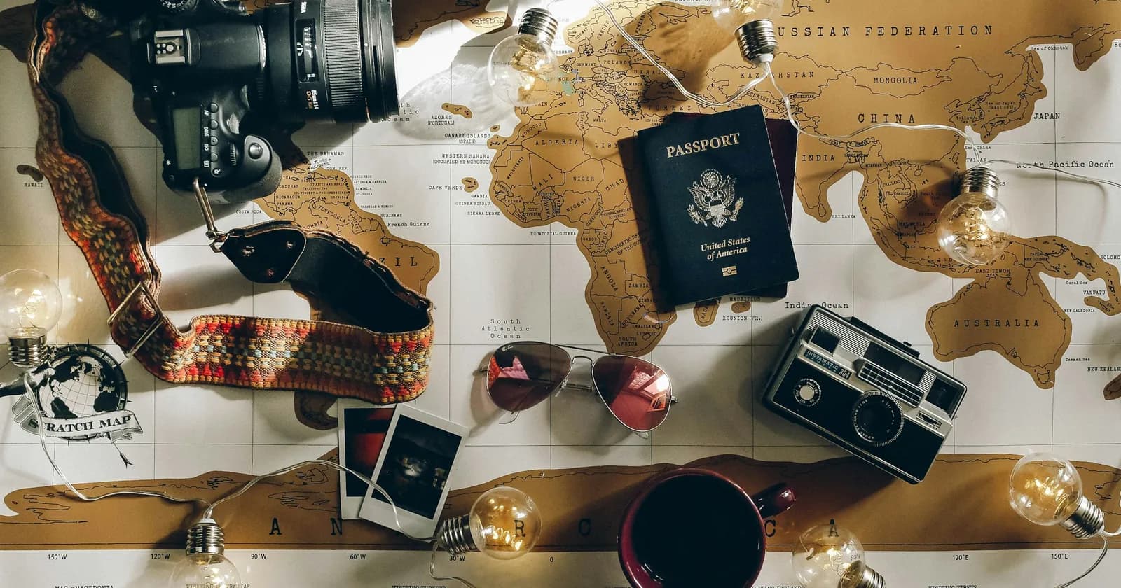 A camera, a closed passport and travel papers on a map