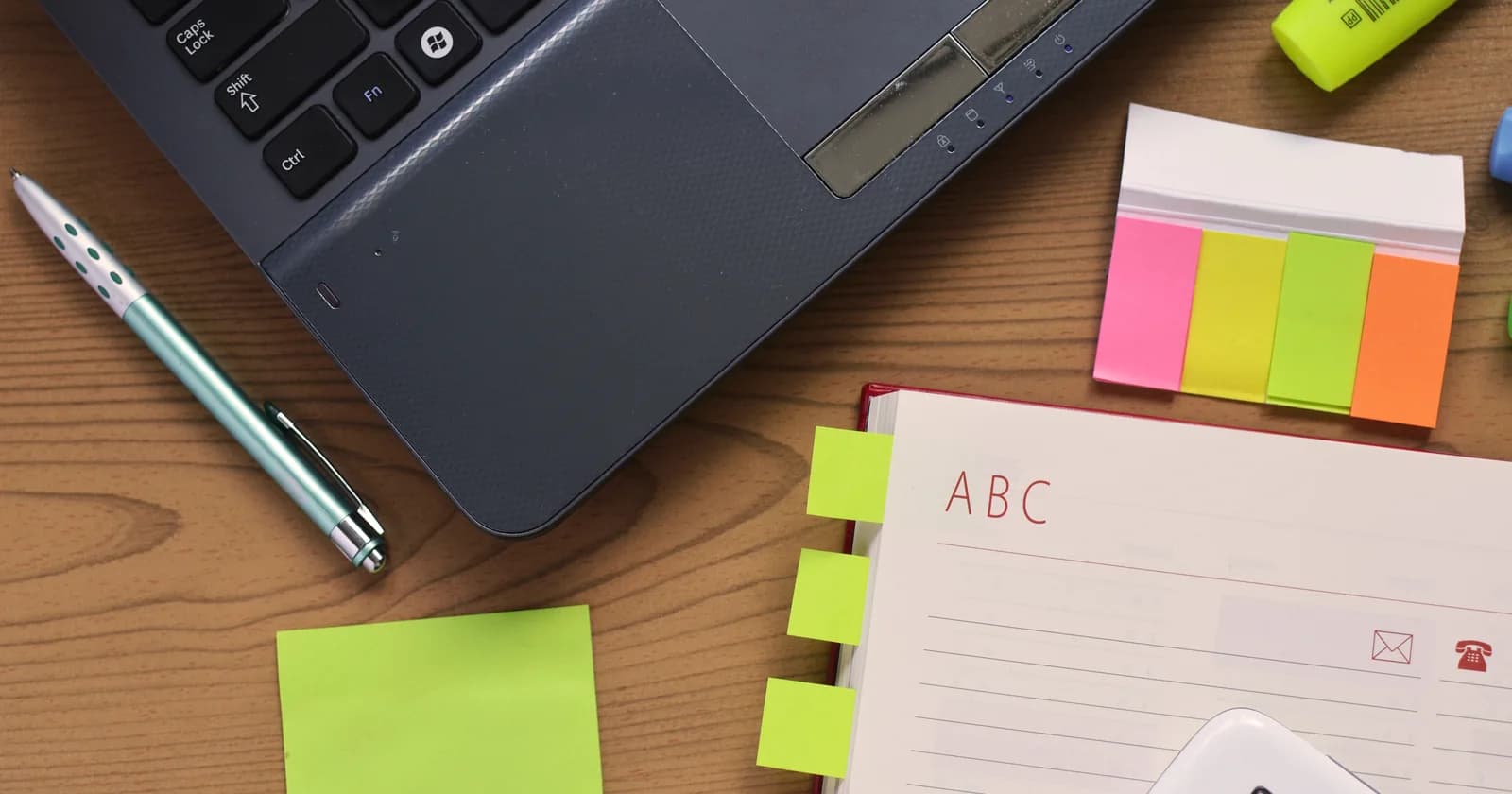 Laptop, notebook and pen arranged on a desk