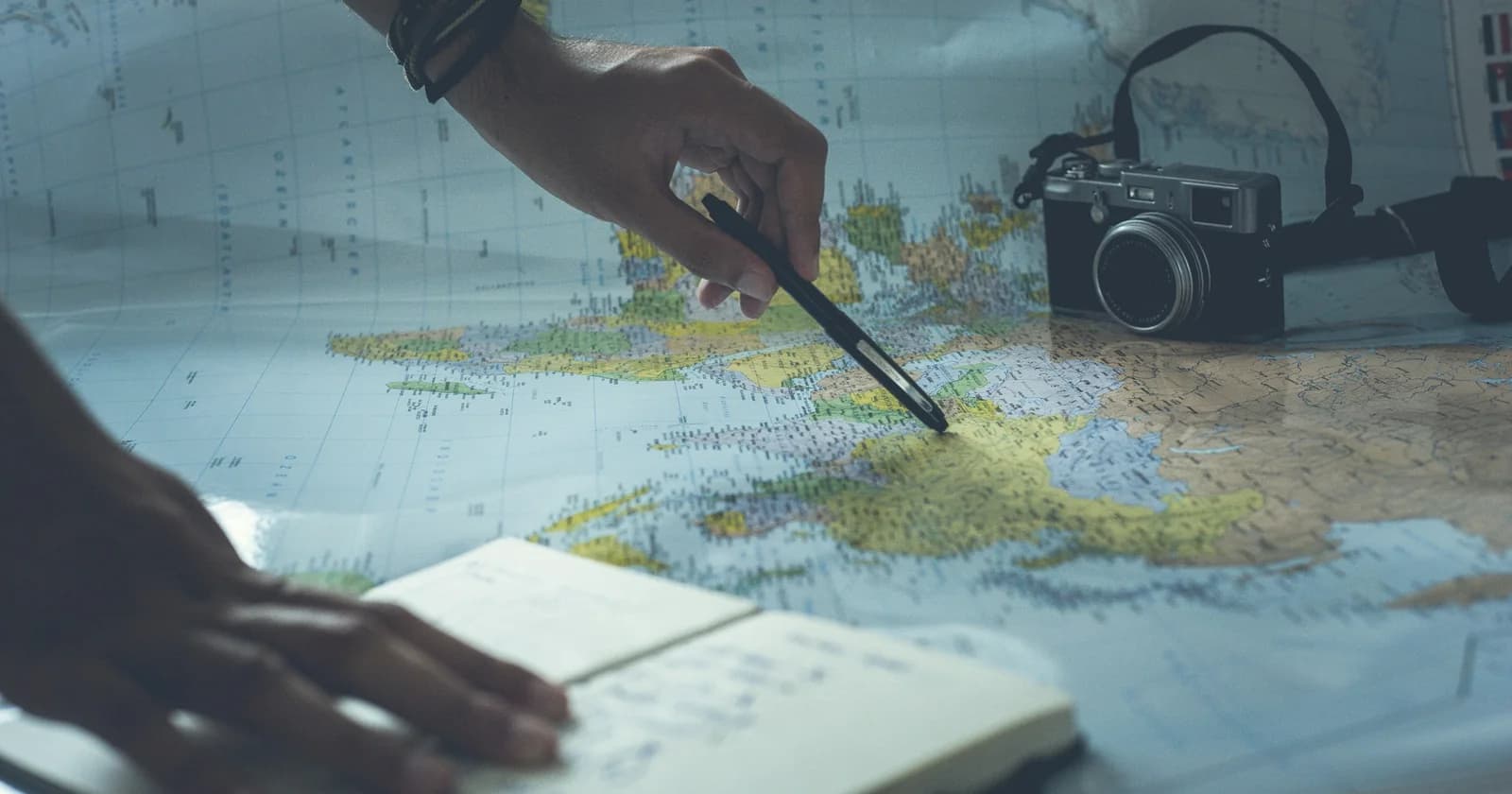 Hands marking a paper map beside a notebook