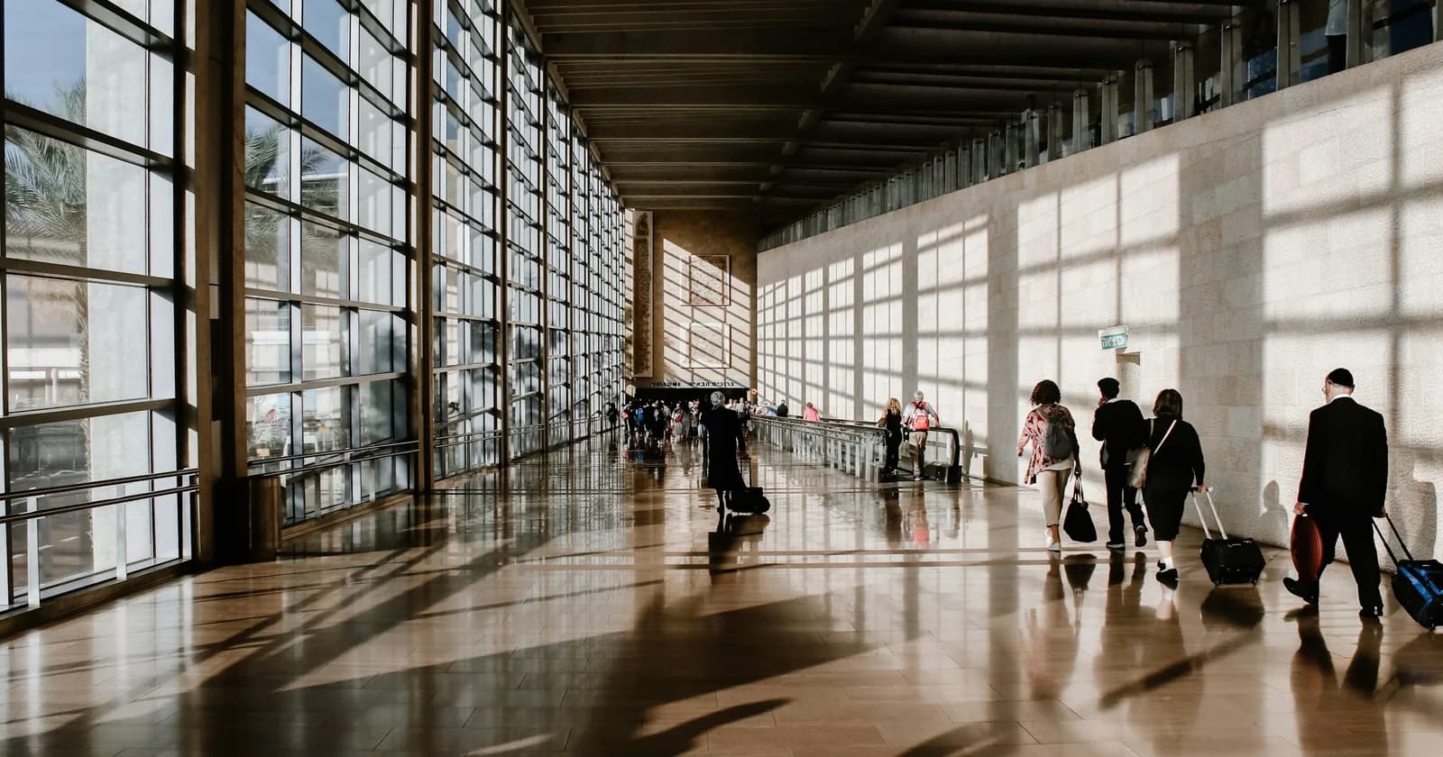 Travellers walking through a sunlit airport concourse
